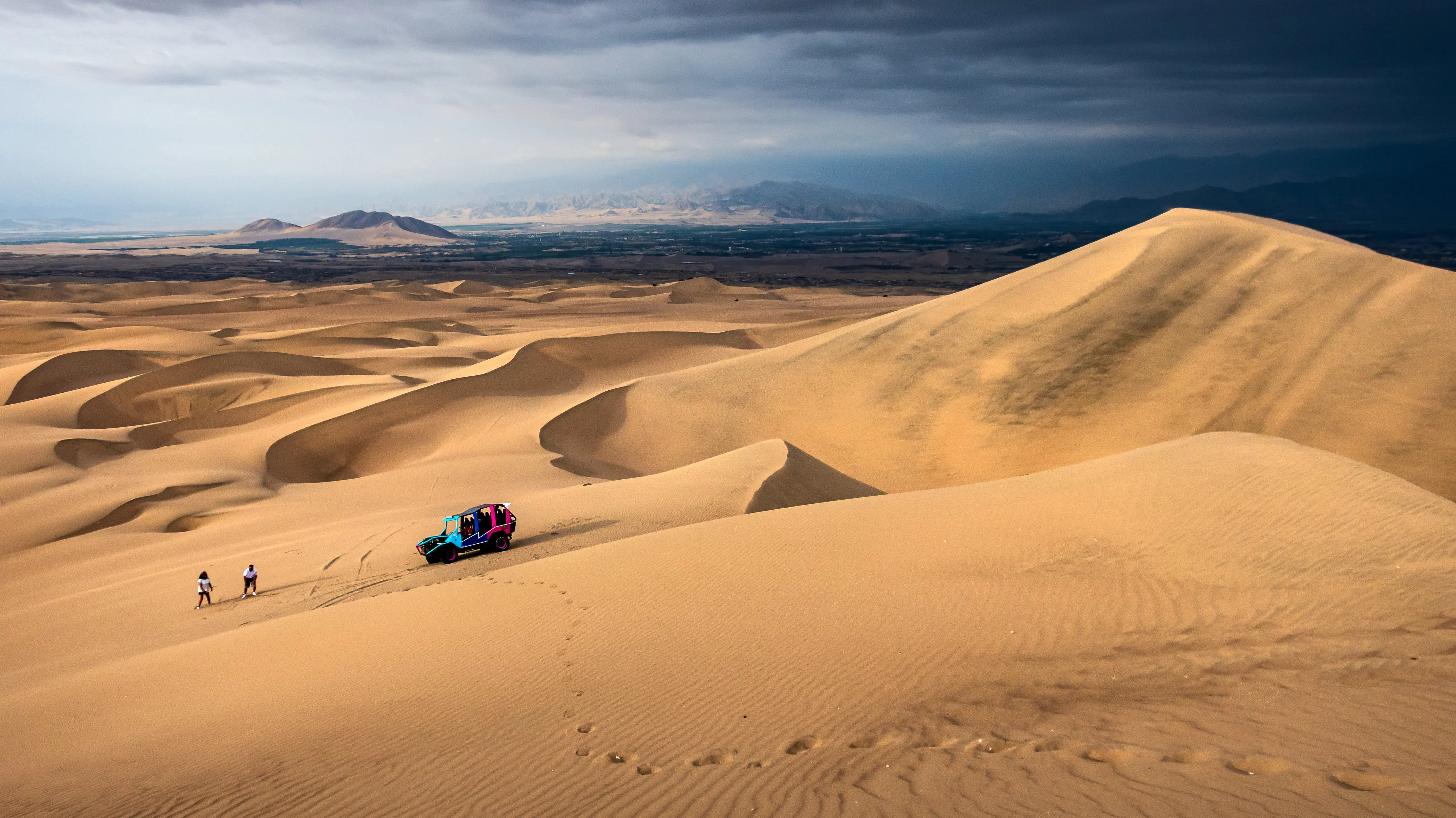 Dune buggy moving across the desert beneath a wide sky