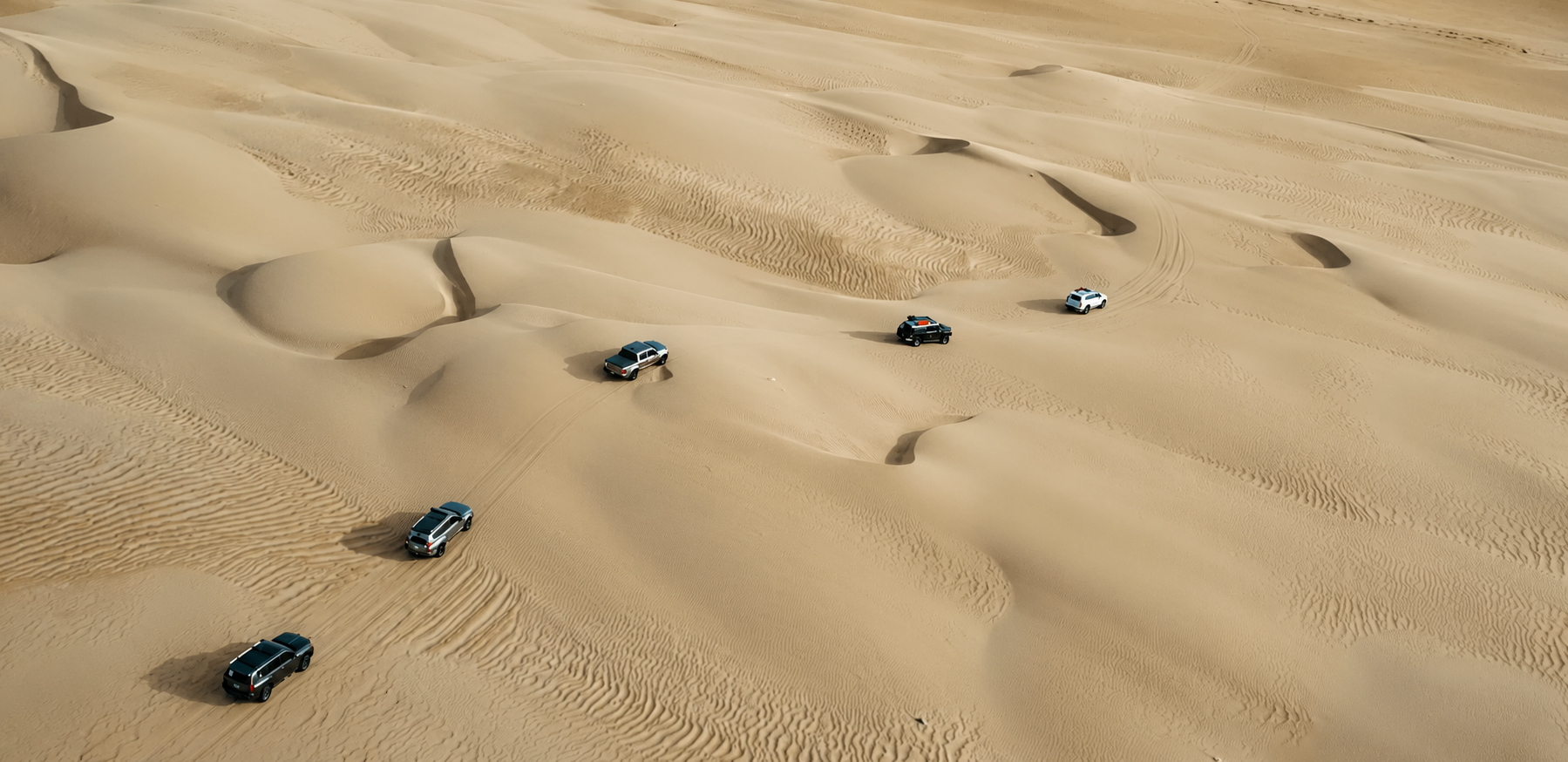 4x4 vehicles crossing desert dunes